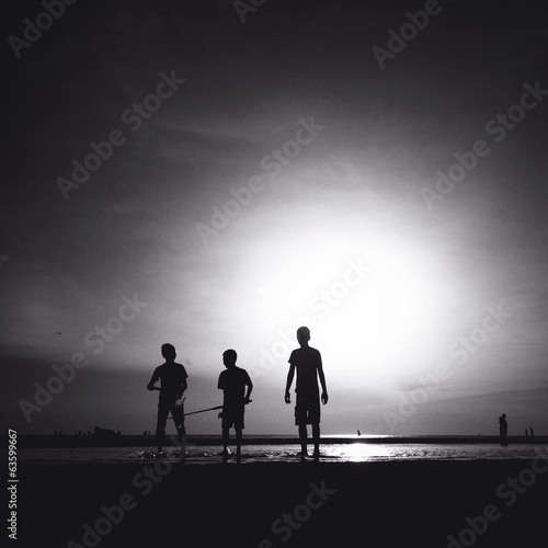 Instant Collection: silhouette of three male friends walking on the beach silhouette of three male friends walking on the beach
