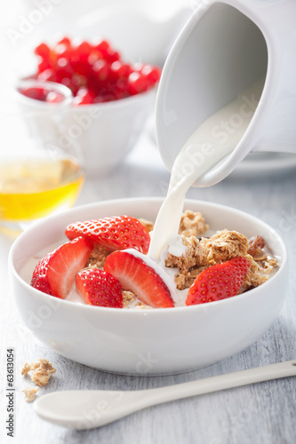 Photo: milk pouring over granola with strawberry for breakfast milk pouring over granola with strawberry for breakfast
