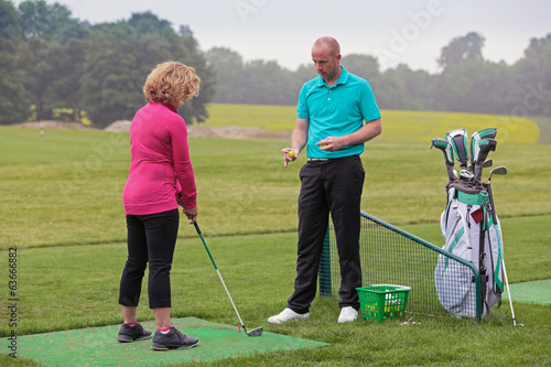 Photo: Lady golfer being taught by a golf pro. Lady golfer being taught by a golf pro.