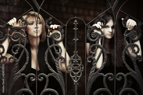 Photo: Two sad young women at the iron fence Two sad young women at the iron fence