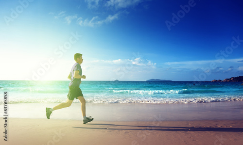 Photo: Man running on tropical beach at sunset Man running on tropical beach at sunset