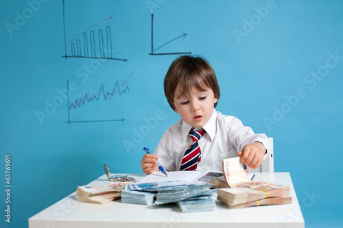 Photo: Young boy, counting money and taking notes Young boy, counting money and taking notes