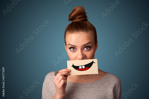 Photo: Happy pretty woman holding card with funny smiley Happy pretty woman holding card with funny smiley