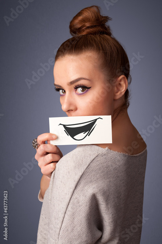 Photo: Happy cute girl holding paper with funny smiley drawing Happy cute girl holding paper with funny smiley drawing