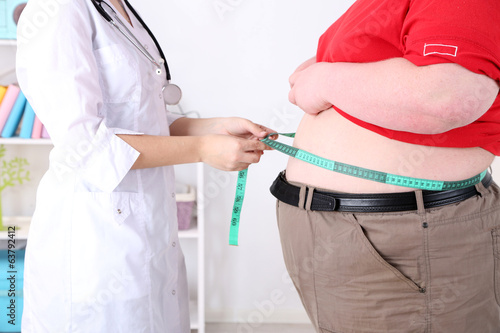 Photo: Doctor examining patient obesity on light background Doctor examining patient obesity on light background
