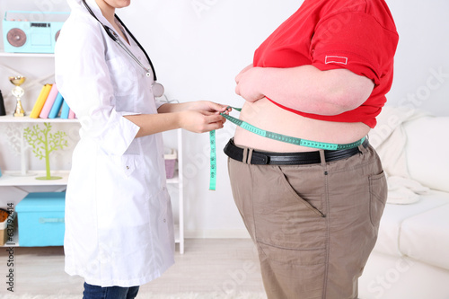 Photo: Doctor examining patient obesity on light background Doctor examining patient obesity on light background
