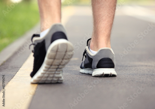 Photo: Runner feet running on road closeup on shoe Runner feet running on road closeup on shoe