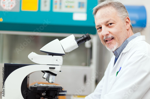 Photo: Scientist conducting research looking through microscope Scientist conducting research looking through microscope
