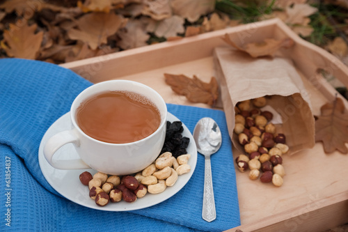 Photo: The cup of tea and the plate with hazelnuts is on a napkin The cup of tea and the plate with hazelnuts is on a napkin