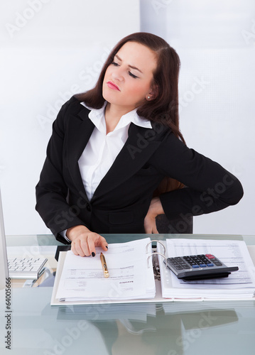 Photo: Tax Consultant Suffering From Backache At Desk Tax Consultant Suffering From Backache At Desk