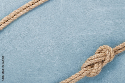 Photo: Ship rope knot on wooden texture background Ship rope knot on wooden texture background