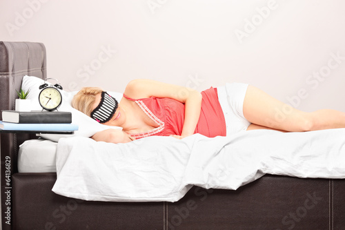 Photo: Woman sleeping with eye mask in a bedroom Woman sleeping with eye mask in a bedroom