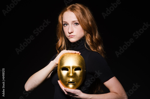 Photo: Redhead woman iwith mask in hypocrisy consept against black bac Redhead woman iwith mask in hypocrisy consept against black bac