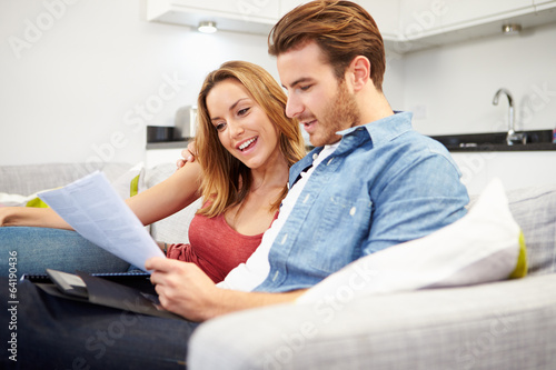 Photo: Young Couple Looking Through Personal Finances At Home Young Couple Looking Through Personal Finances At Home