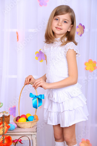 Photo: Beautiful small girl holding basket with colorful eggs Beautiful small girl holding basket with colorful eggs