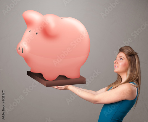 Photo: Young girl holding a huge savings piggy bank Young girl holding a huge savings piggy bank