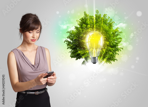 Photo: Young girl presenting idea light bulb with green tree Young girl presenting idea light bulb with green tree
