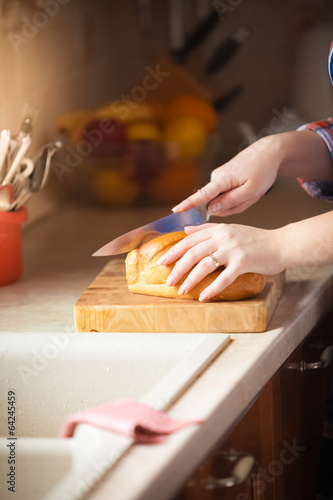 Photo: photo of woman cutting bread on wooden desk photo of woman cutting bread on wooden desk