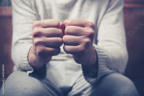 Photo: Man on sofa with clenched fists Man on sofa with clenched fists