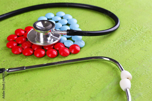 Photo: Heart of pills and stethoscope on wooden background Heart of pills and stethoscope on wooden background