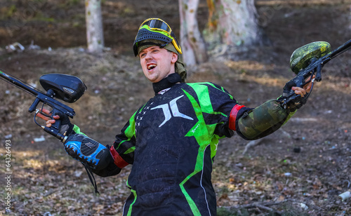 Photo: Happy paintball player with two guns Happy paintball player with two guns