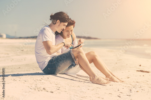 Photo: Young Couple at Seaside with Digital Tablet Young Couple at Seaside with Digital Tablet