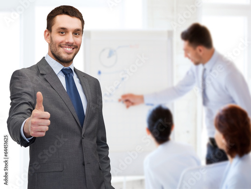 Photo: handsome buisnessman showing thumbs up in office handsome buisnessman showing thumbs up in office