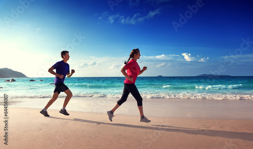 Photo: Man and women running on tropical beach at sunset Man and women running on tropical beach at sunset