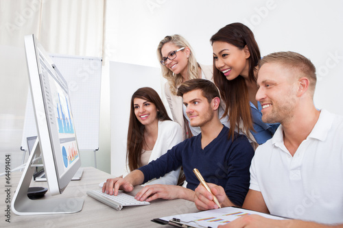 Photo: Smiling Businesspeople Using Desktop PC Smiling Businesspeople Using Desktop PC