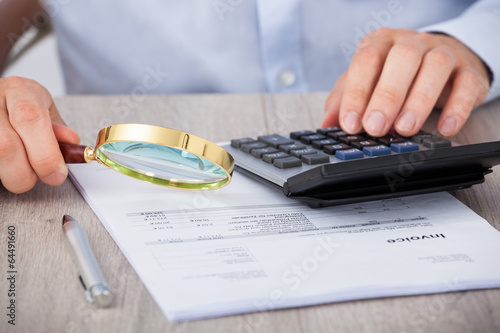 Photo: Male Auditor Scrutinizing Financial Documents Male Auditor Scrutinizing Financial Documents