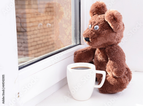 Photo: Toy-bear looking out window close-up Toy-bear looking out window close-up