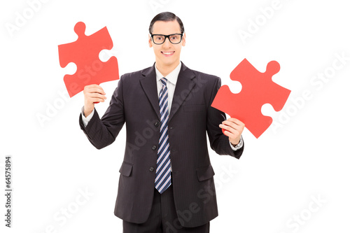 Photo: Young businessman holding two pieces of puzzle Young businessman holding two pieces of puzzle