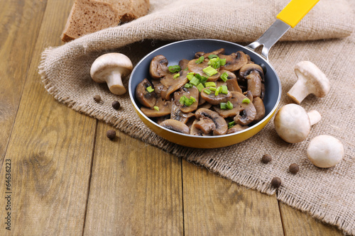 Photo: Delicious fried mushrooms in pan on table close-up Delicious fried mushrooms in pan on table close-up