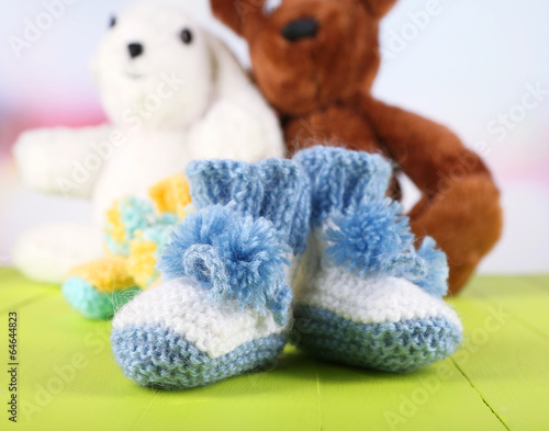 Photo: Crocheted booties for baby and toys,on color background Crocheted booties for baby and toys,on color background