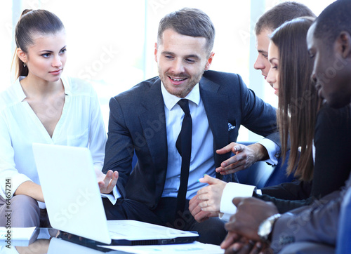 Photo: Group of friendly businesspeople gathered in front of laptop Group of friendly businesspeople gathered in front of laptop