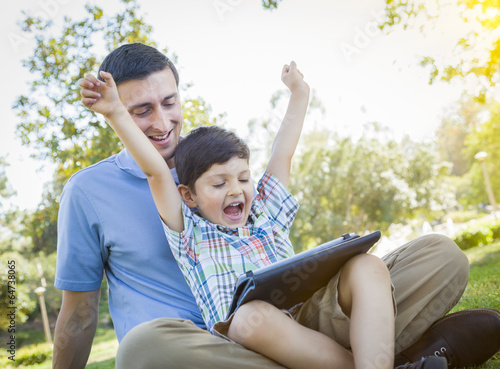 Photo: Handsome Mixed Race Father and Son Playing on Computer Tablet Handsome Mixed Race Father and Son Playing on Computer Tablet
