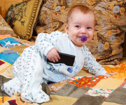 Photo: Funny baby with dummy and cell phone in his hand Funny baby with dummy and cell phone in his hand