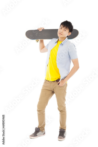Photo: confident young man standing and holding a skateboard confident young man standing and holding a skateboard