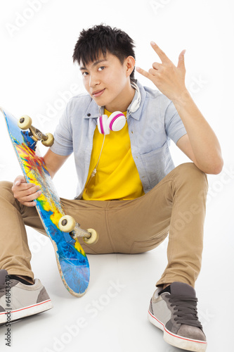 Photo: skateboard man sitting and make a rock gesture skateboard man sitting and make a rock gesture
