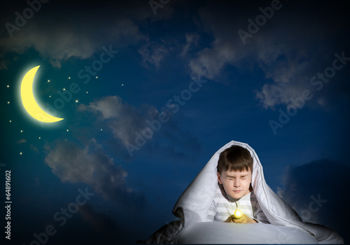 Photo: boy under the covers with a flashlight boy under the covers with a flashlight