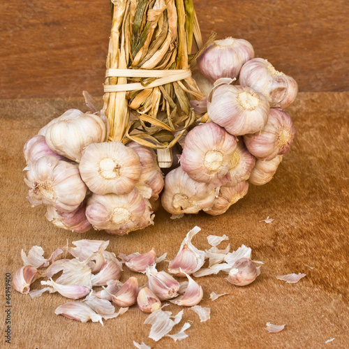 Photo: garlic on brown textured wood.It is a herb. garlic on brown textured wood.It is a herb.