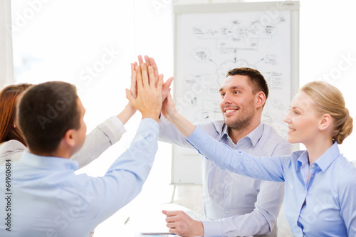 Photo: happy business team giving high five in office happy business team giving high five in office