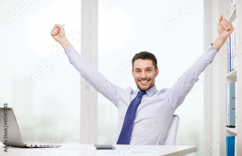 Photo: smiling businessman with laptop and documents smiling businessman with laptop and documents