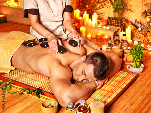 Photo: Man getting stone therapy massage . Man getting stone therapy massage .