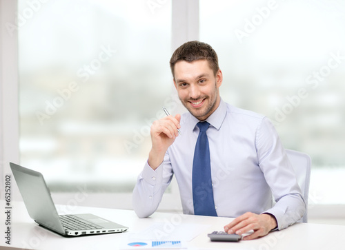 Photo: smiling businessman with laptop and documents smiling businessman with laptop and documents