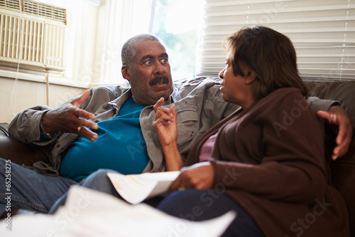 Photo: Worried Senior Couple Sitting On Sofa Looking At Bills Worried Senior Couple Sitting On Sofa Looking At Bills