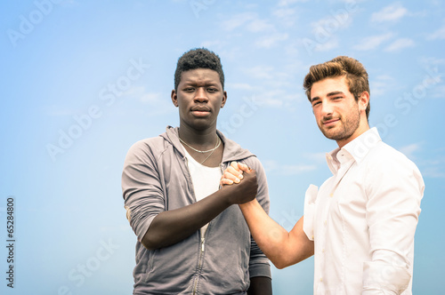 Photo: Afroamerican and caucasian men shaking hands against racism Afroamerican and caucasian men shaking hands against racism