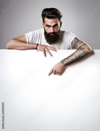 Photo: Handsome bearded man holding blank poster. Handsome bearded man holding blank poster.