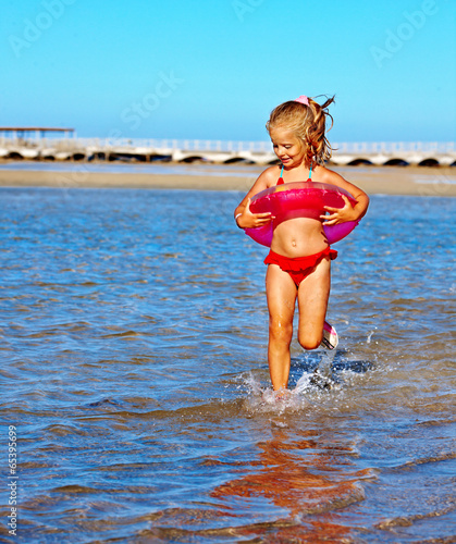 Photo: Child with beach ring running on beach. Child with beach ring running on beach.
