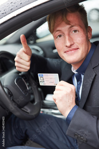 Photo: Junger Mann im Auto hält Daumen hoch und Führerschein Junger Mann im Auto hält Daumen hoch und Führerschein